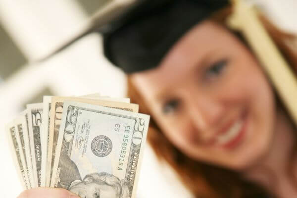 Picture of a lady in graduation cap with cash for this is how to graduate debt free.