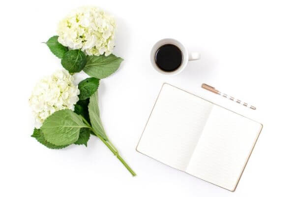 Picture of flowers, coffee, and a notebook to show how to live simply and cheaply.