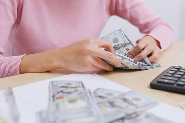 Picture of someone counting out money for how to save $1000 in a year with envelopes.