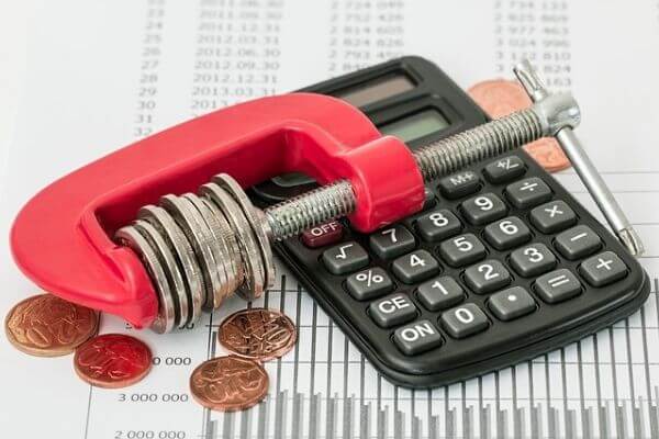 A picture of a wrench with coins to make sure you reduce your liabilities and debts.