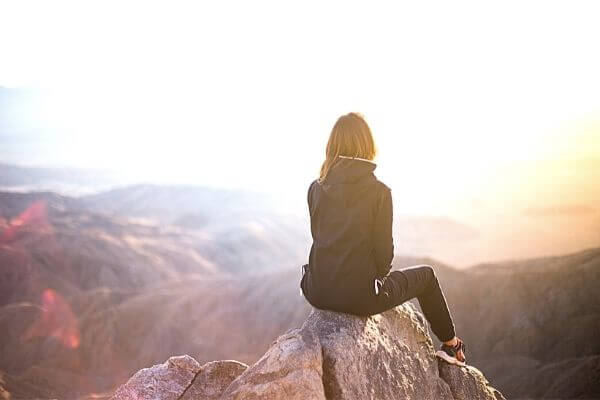 Picture of someone sitting on a cliff as they contemplate their money blocks.