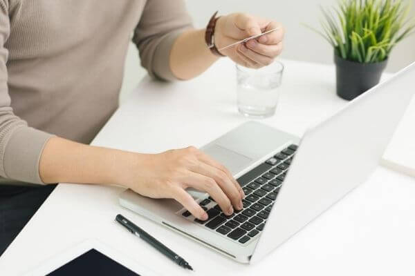 Image of a computer and card in someone's hand to see can you live on $70000 per year.