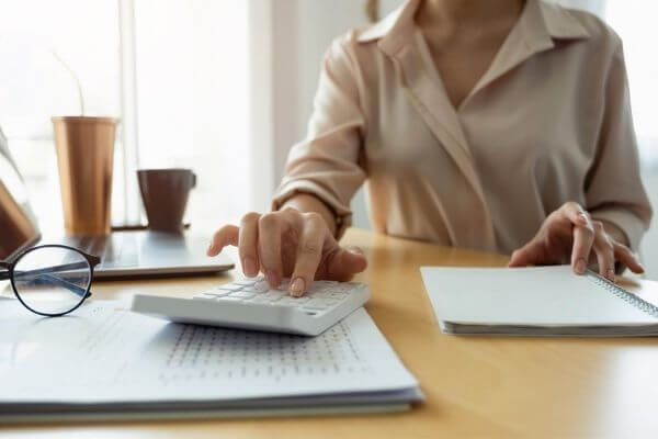 A picture of a person using a monthly bill calendar and calculator. 