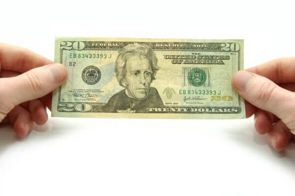 Image of a cash in someone's hand to see can you live on $90000 per year.