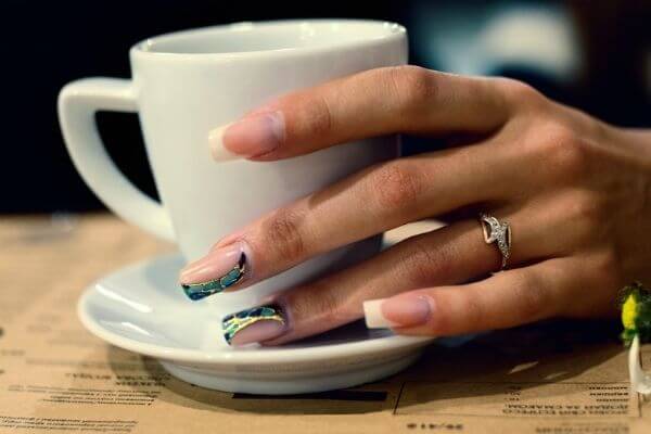 Picture of a Left hand on a coffee mug wondering about left hand itching spiritual meaning.