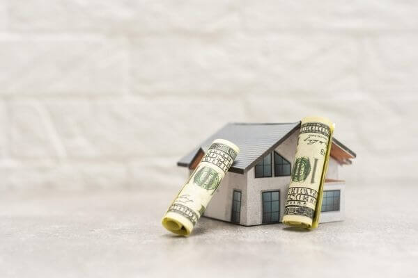 Picture of a house and money for frugal green home ownership. 