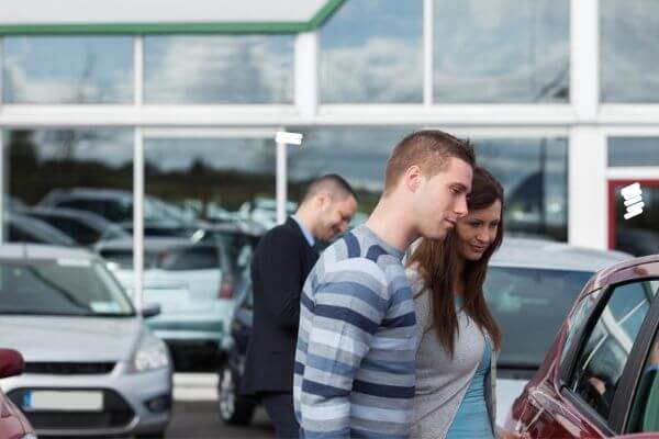 Picture of a couple looking at a car discussing is a car an asset or liability.