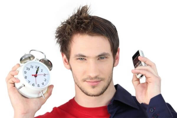 Picture of a guy with an alarm clock wondering what time does the average billionaire wake up.