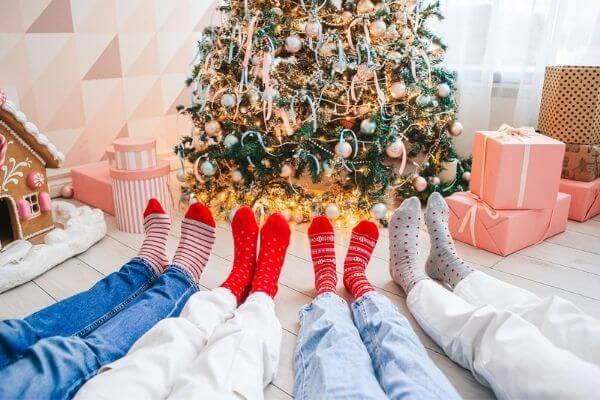 Picture of people in Christmas socks by the tree.