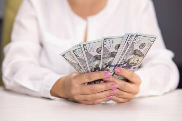 Picture of a lady holding a bunch of hundred dollar bills for millionaire quotes about money.