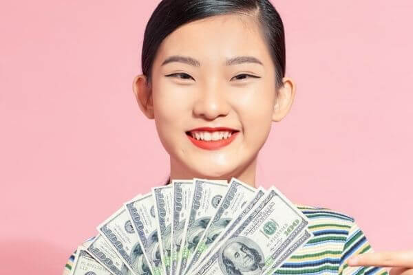 Picture of a young adult holding cash for savings tools to build cash fund savings.