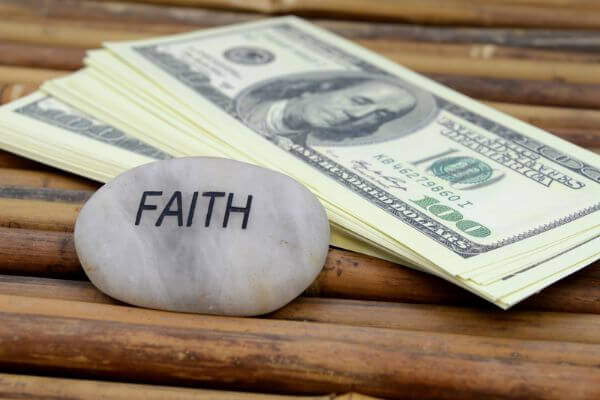 Picture of hundred dollar bills and a rock with the word faith for do money affirmations really work.