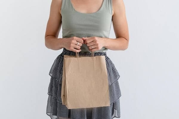 Picture of a lady with a brown paper bag for frugal green ideas when shopping.