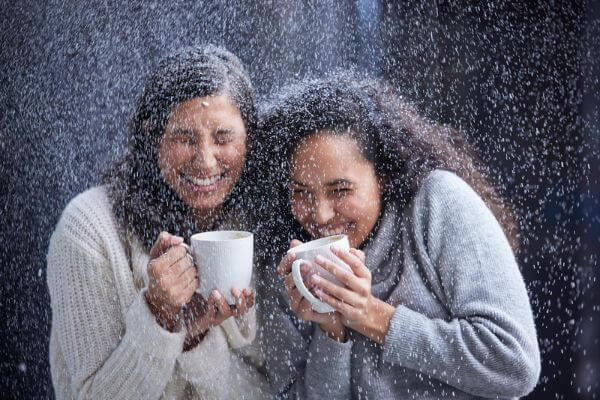 Picture of friends giggling while it is snowing outside for when to give surprise money gift ideas.