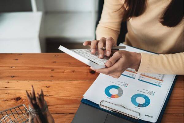 Picture of a lady and calculator trying to create a personal financial statement.