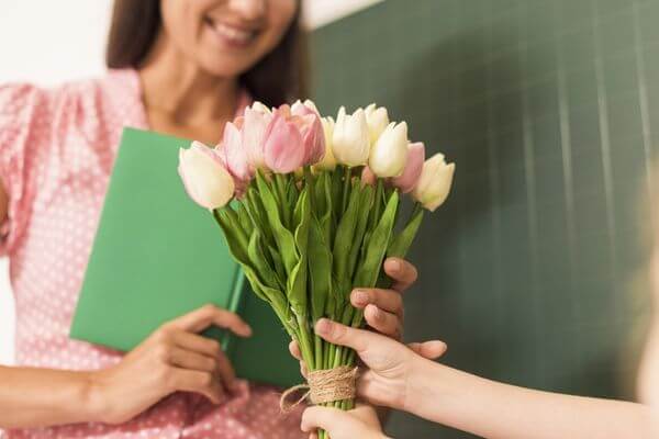 Picture of a child handing flowers to a teacher for consumable teacher gifts. 