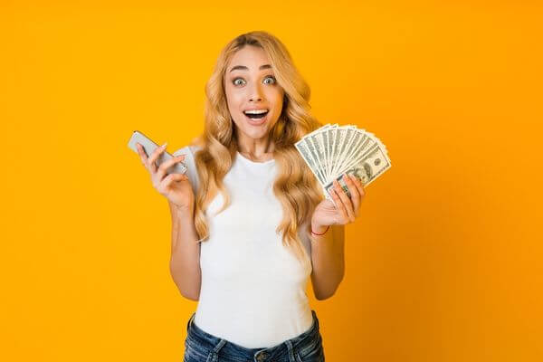 Picture of an excited lady with cash for ways to maximize your profits when flipping money.