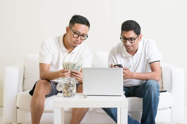 Two guys working on a laptop to make money.