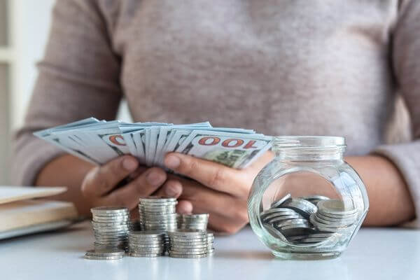 Picture of a lady counting money for how to save 20000 in a year.