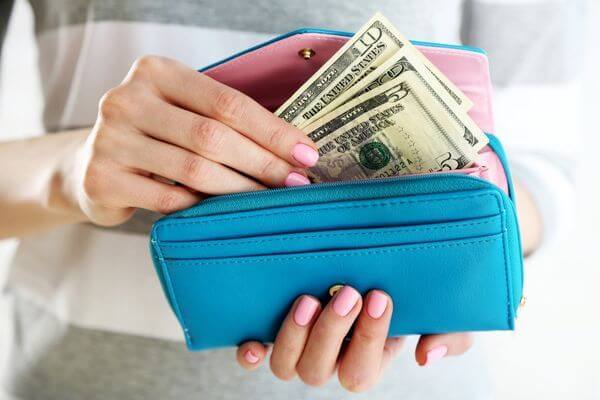 Picture of a lady pulling cash from a wallet for the best frugal home must haves to save money.