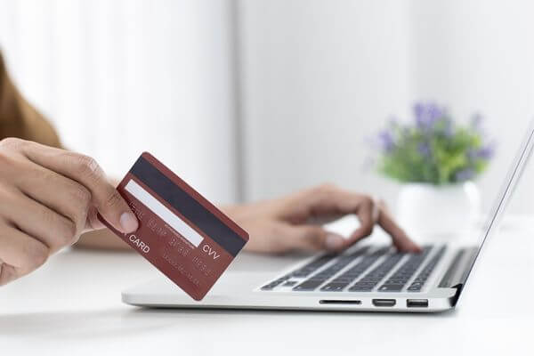 Picture of someone using a credit card for an online purchase.