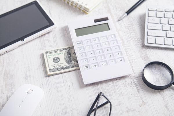 Picture of a calculator and hundred dollar bills.