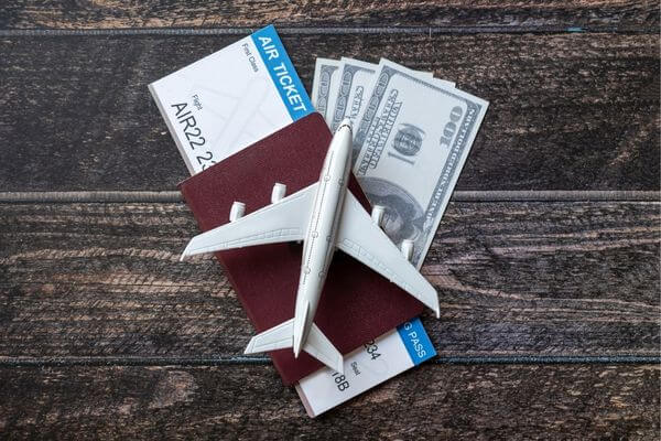 Picture of a passport, cash and plane for the risks of flying with cash.