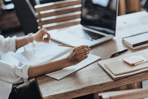 Picture of a person working at a laptop with a notebook for how many working days are typically in a year.