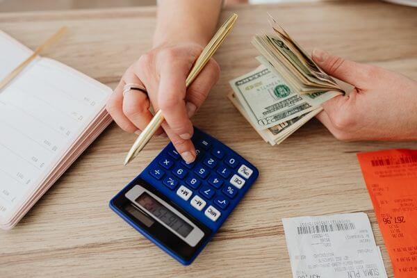 Picture of a calculator and coins to figure how much is 37k a year hourly salary.