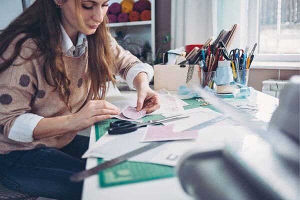 Picture of a lady making a vision board with a list of vision board supplies.