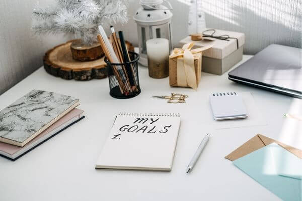 Picture of a desk with a notebook that says my goals.