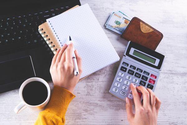 Picture of a calculator and paper to figure out 54k salary hourly calculator.