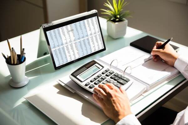 A picture of person sitting at a computer, looking at a calculator screen with the words "liquid net worth" written on it