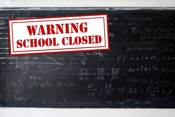 Picture of a chalkboard with a sign that says warning school closed.