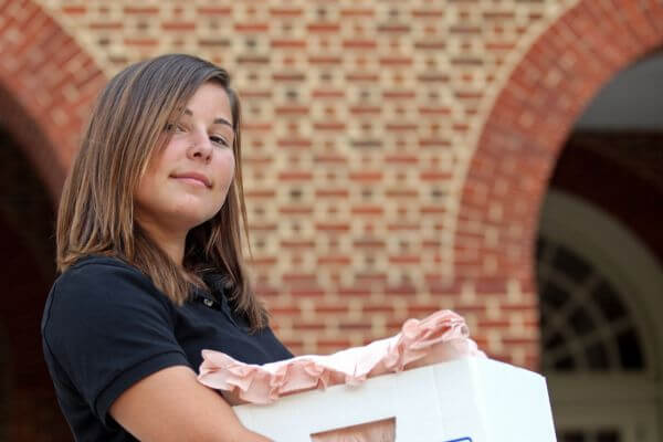 Picture of young adult carrying a moving box for how to move out at 18.