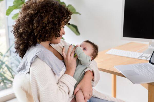 Picture of a mom giving a bottle while working.