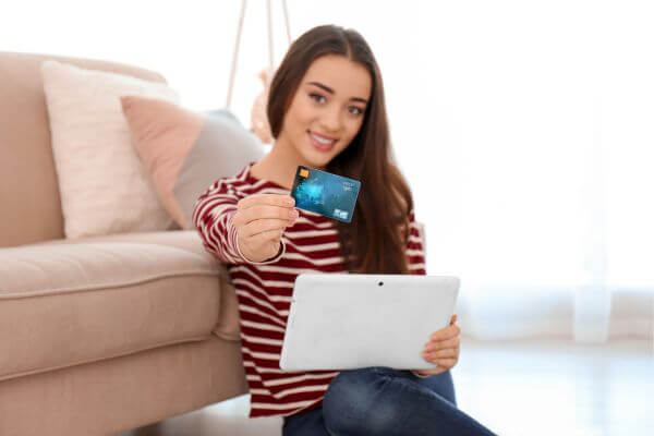 A picture of woman holding her card and tablet. 