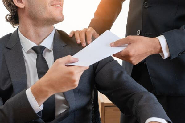 Picture of an employee receiving his salary in a white envelope given by his employer.