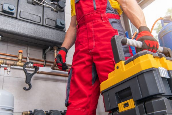 The picture of a HVAC technician fixing, carrying his tools and wearing a safety uniform and gloves.