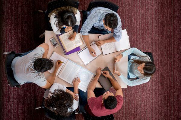 Image of a college students doing a group study together with their books, pens, and noteboks.