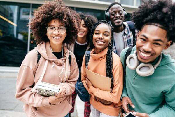 Picture of a college students holding notebooks and folder while smiling together.