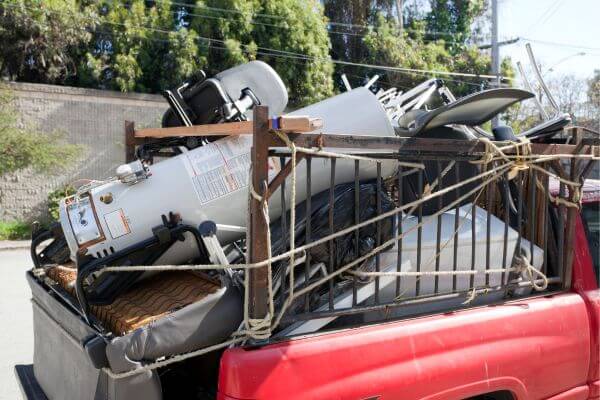 The image of a old junk stuff collected together and tied up in the  pick up car.