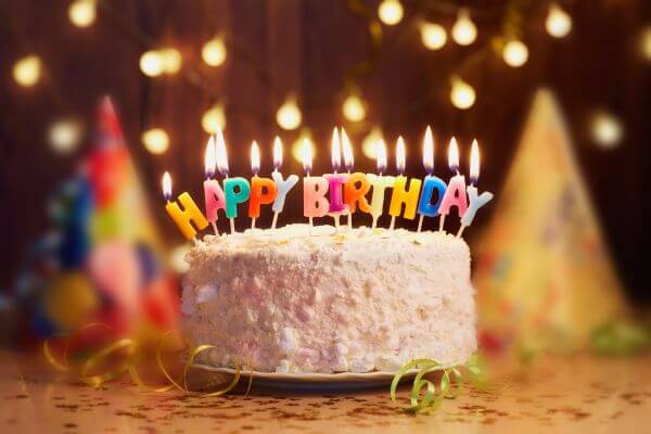 Image of a  cake with Happy Birthday candle light and stuff around.