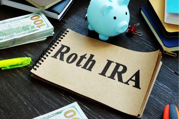 Picture of the binder with the text of Roth IRA, piggy bank blue, money, and other stuff around.