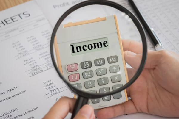 Image of the accounting sheet, calculator with a text of income, a magnifier glass, and a hand.