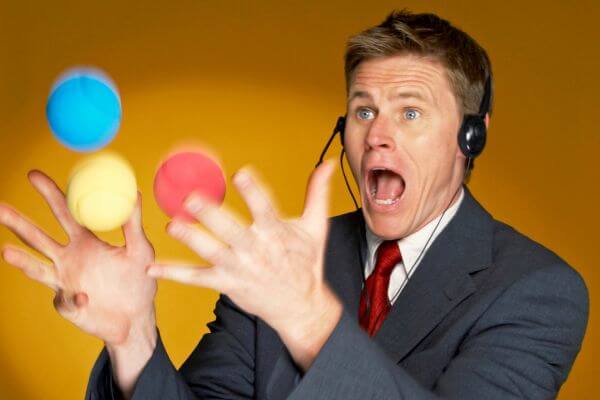 Image of the man in a suit and headset with a microphone juggling the colorful balls.