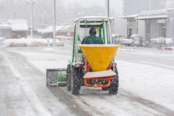 Image of a worker in a mini truck plowing a snow along the way.