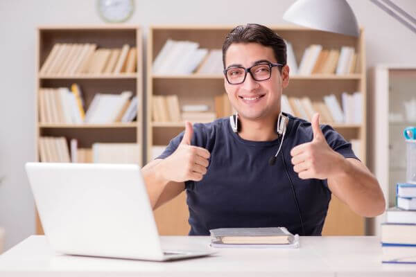 Image of the man wearing eyeglass, earphone with microphone and a laptop in his desk.