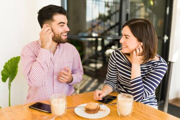 Picture of the  man and woman  listening to a music in earpad and  dating in a restaurant. 