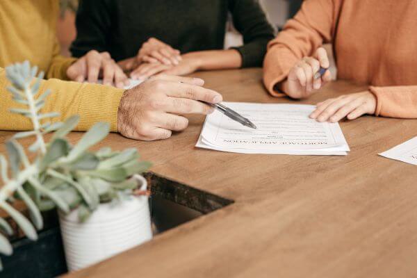 Image of the  man and women holding a pen and explaining the content of the form. 